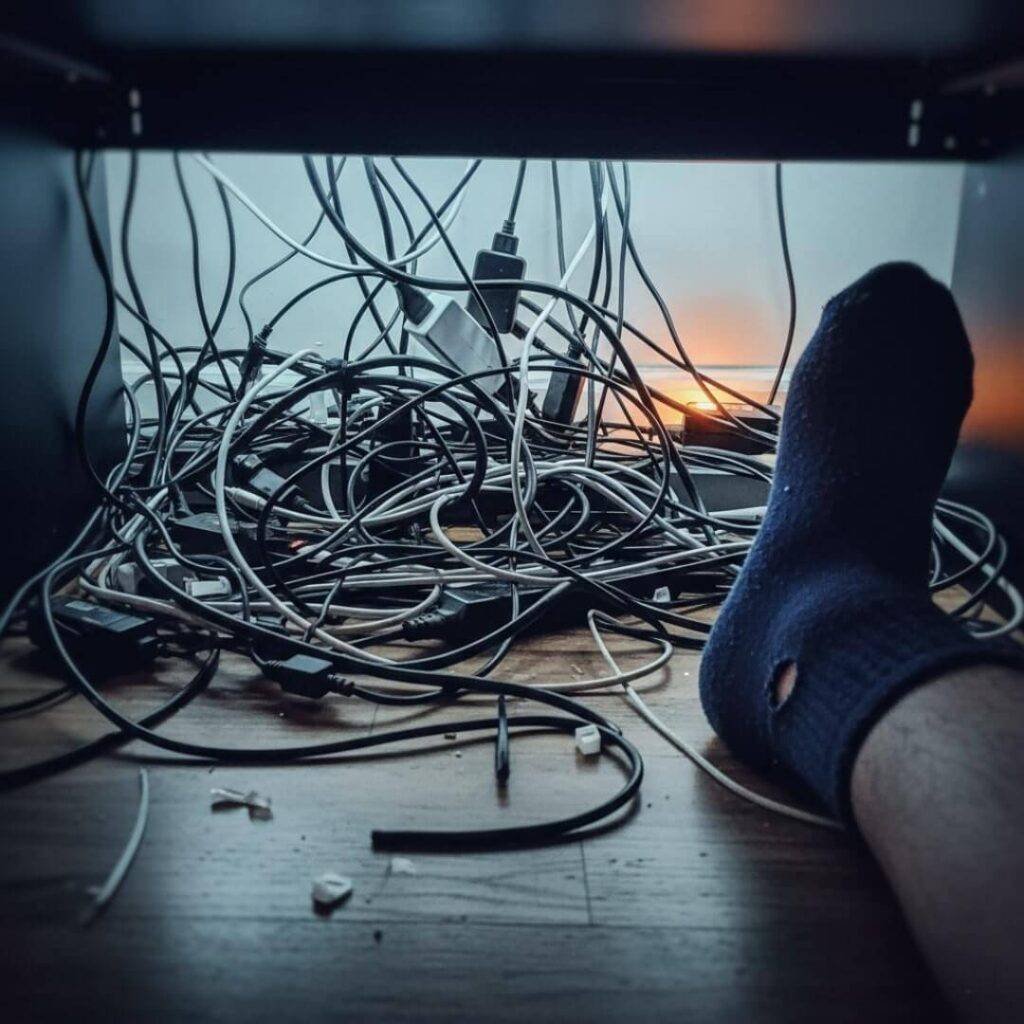 Blurry 3 AM selfie of tangled cables and socked foot.