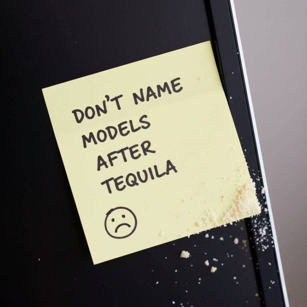 A sticky note on a monitor reads "DON'T NAME MODELS AFTER TEQUILA" with crumbs.
