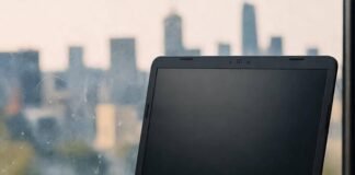 Best Budget Laptops in 2025: Top Picks for Affordable Performance Blurred laptop on coffee cups and notebook, city skyline, sock, cassette sticker.